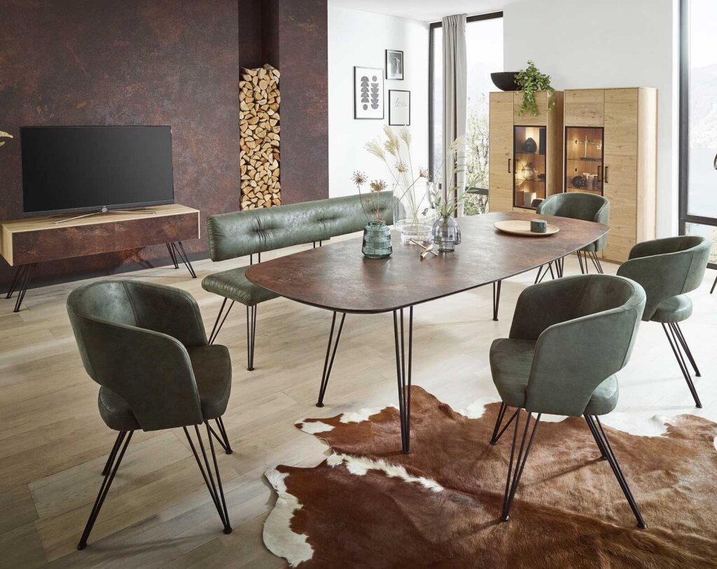 Eine Sitzgruppe mit einem Tisch aus einer robusten MDF Tischplatte Steinoptik (Rostfarben). Graziles Tischgestell aus Metall. Dazu passende Stühle, Ledergepolstert in einem Grünton.