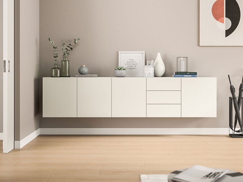 Ein Highboard aus hochwertigen mattierten Dekorplatten in off-white hängt an der Wand. Es hat fünf Segmente, davon vier als Drehtür und ein Segment mit drei Schubladen. Auf dem Sideboard stehen Vasen und Töpfe mit Pflanzen, Bücher und ein gerahmter Spruch "Stay positive, work hard, make it happen." Die Atmosphäre ist hell, freundlich und modern.