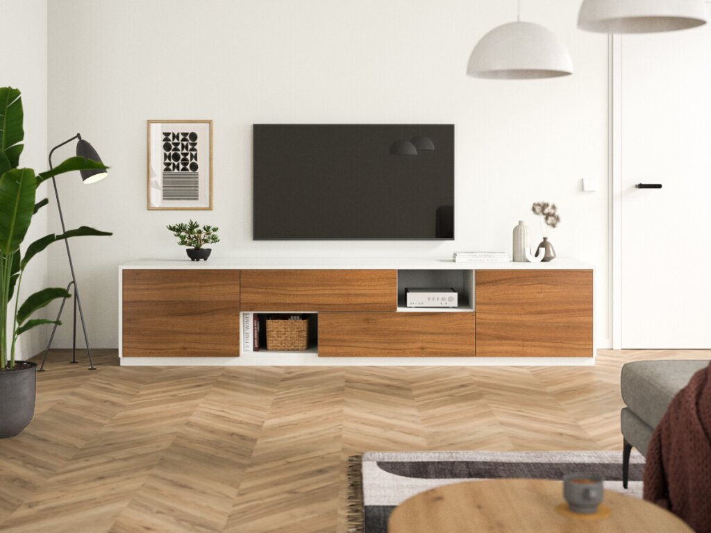 Ein bodenstehendes Sideboard mit weißem Rahmen und Fronten aus Nussholz. Links und rechts je eine Drehtür oder Klapptür, mittig zwei Laden und je ein kleines, offenes Regalfach. Über dem Sideboard hängt ein Flachbildschirmfernseher, daneben stehen kleinere Dekorationsobjekte. Links im Bild eine moderne Lampe mit zartem Stahlgestell, rechts eine angeschnittene Couch und ein Couchtisch.